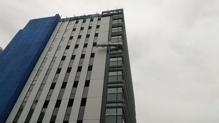 Tall building with people working in a skewed gondola