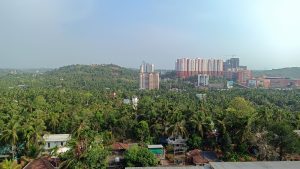 Picture taken from the top floor balcony. Greenish plants, building etc.  