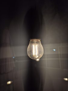 View larger photo: Radiant light bulb illuminating brightly against a dark background.