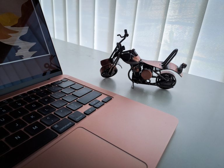 A laptop and a miniature of a motorbike in an office desk