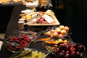 An assortment of fruits and cheeses displayed on a buffet table, including cherries, apricots, plums, grapes.