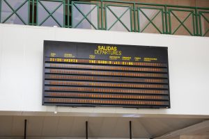 Departures panel at an airport with text in English and Spanish