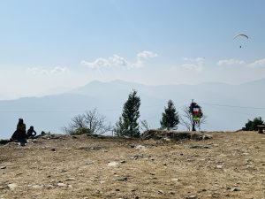 View larger photo: A clear sky with mountains in the background, where people are paragliding.