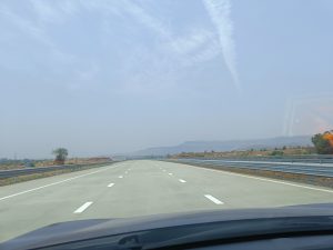 Empty highway with clear sky and faded mountains captured from the car