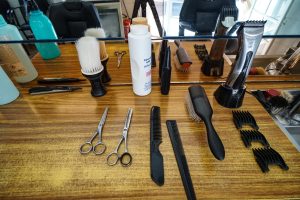A wooden countertop in a barbershop or salon shows an assortment of grooming tools
