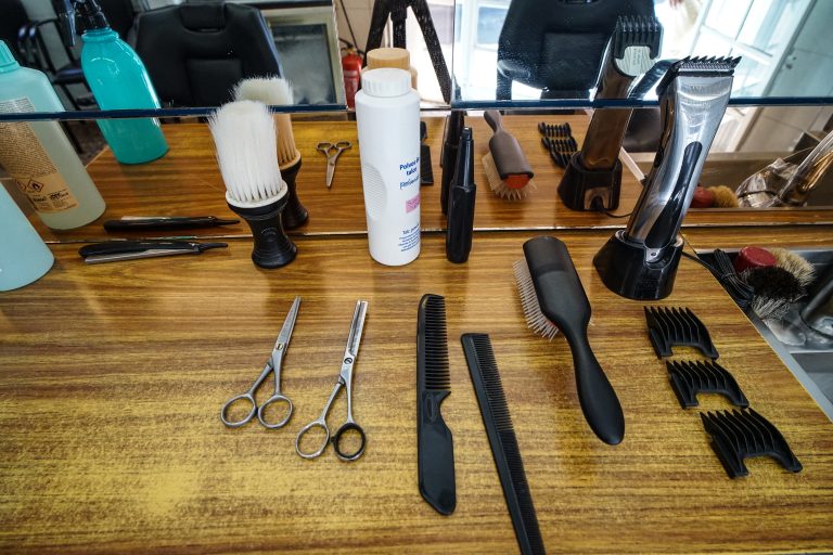 A wooden countertop in a barbershop or salon shows an assortment of grooming tools