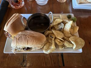 A french dip sandwich with au jus and kettle chips.