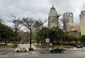 View larger photo: A park in Taipei with a road and cars in the foreground, and high-rise buildings in the background.