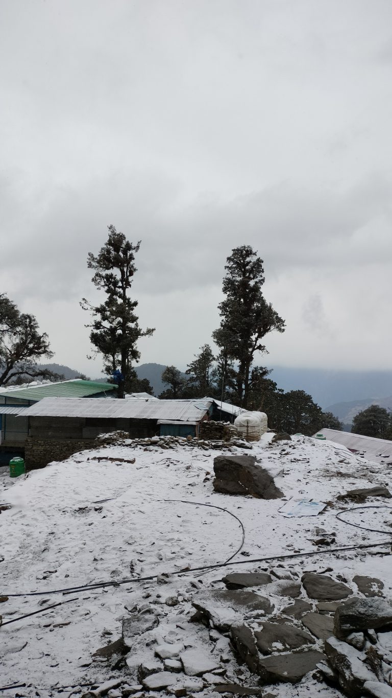 Snowfall on homes at chopta trek, Himalaya ranges visible behind