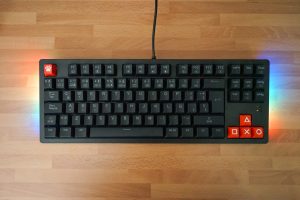 Small gaming keyboard on a wooden table. RGB lights are glowing at the sides.