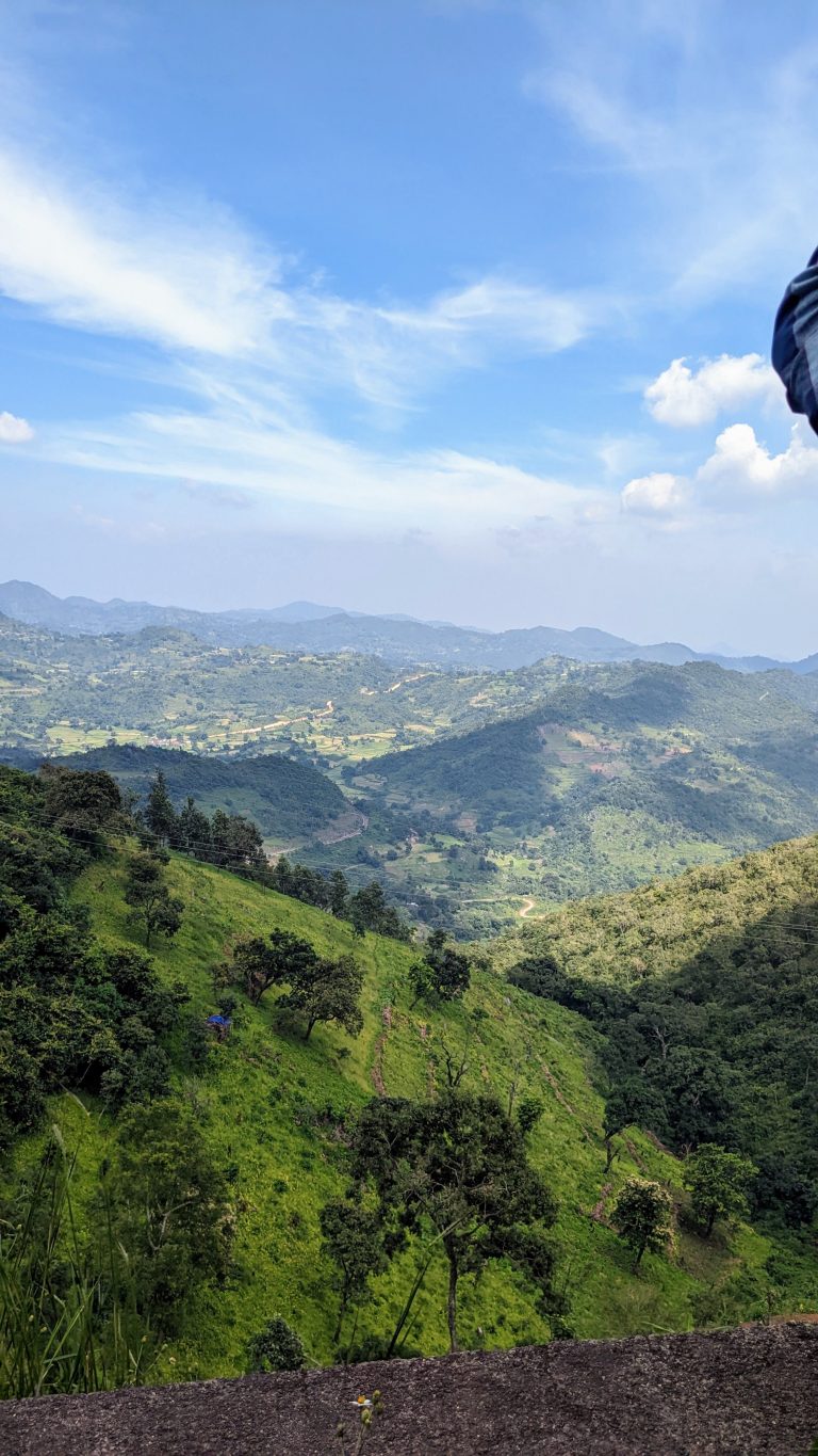 Scenic view from Araku Hill, extending into the distance with mountains in the background under a blue sky with wispy clouds.