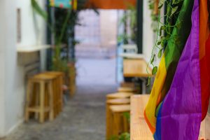 6-Color Pride Flag inside of a bar with wooden furniture.