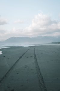 View larger photo: View of a beach on the Oregon coast with a group of people walking in the distance.