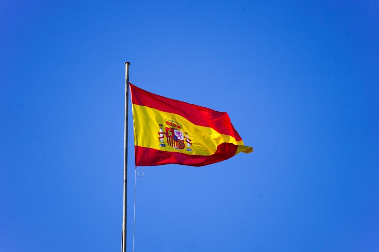 Spanish flag waving over a clear blue sky