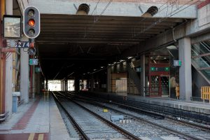 Train tunnel on a train station with two visible sets of tracks and and red traffic light on