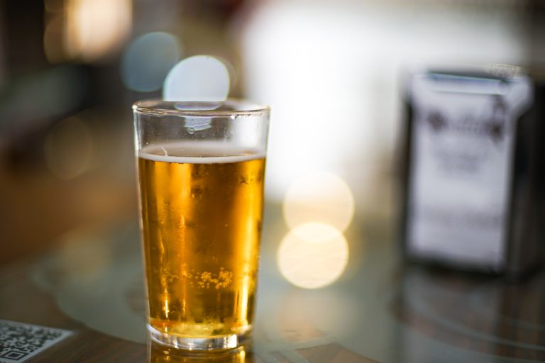 Glass of beer on a bar table with background blurred out