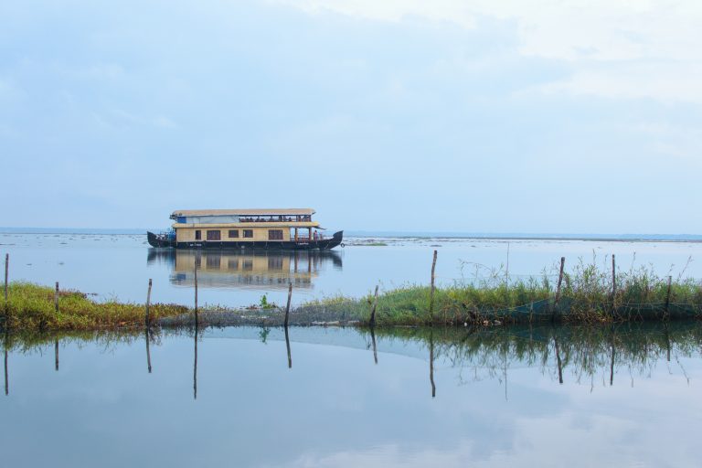 A scenic visual of a houseboat cruising through backwaters at Kumarakom, Kerala, India