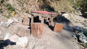 An outdoor rustic wooden table with a red painted top and four wooden stumps used as stools