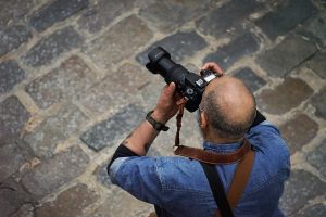 Top view of a photographer taking a photo in the street with a telephoto lens
