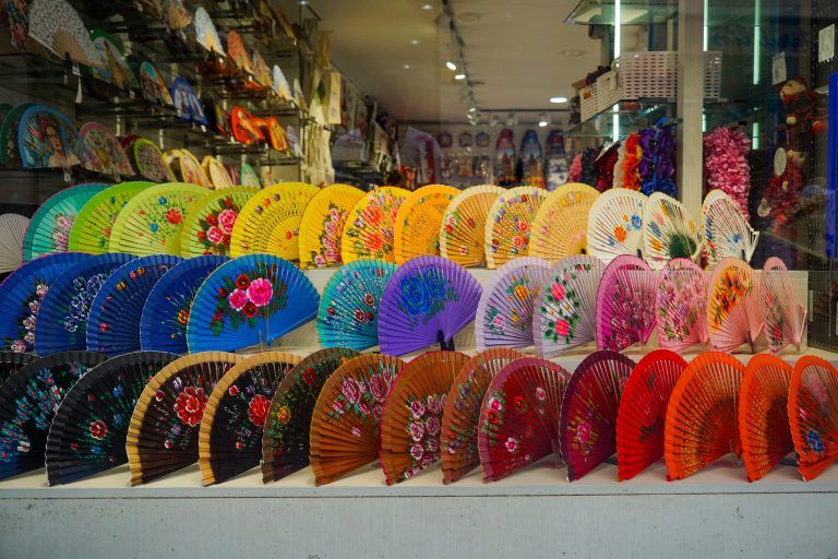 Dozens of rainbow-colores fans in a show window.