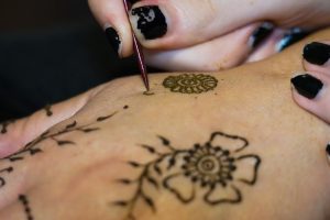 View larger photo: Artist painting mehndi floral motives with henna on a woman's hand