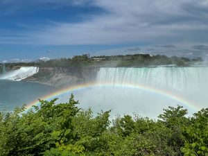 A rainbow over the Canadian Horseshoe Falls with the American Falls in the background at Niagara Falls