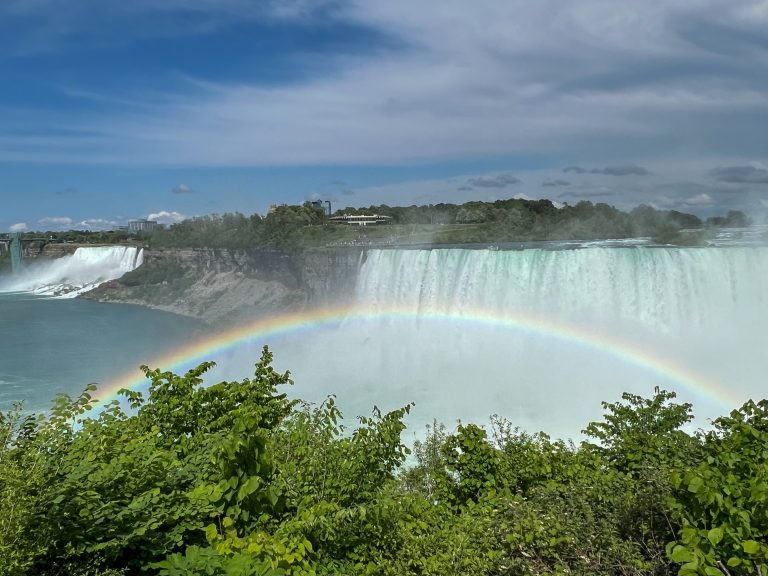 A rainbow over the Canadian Horseshoe Falls with the American Falls in the background at Niagara Falls