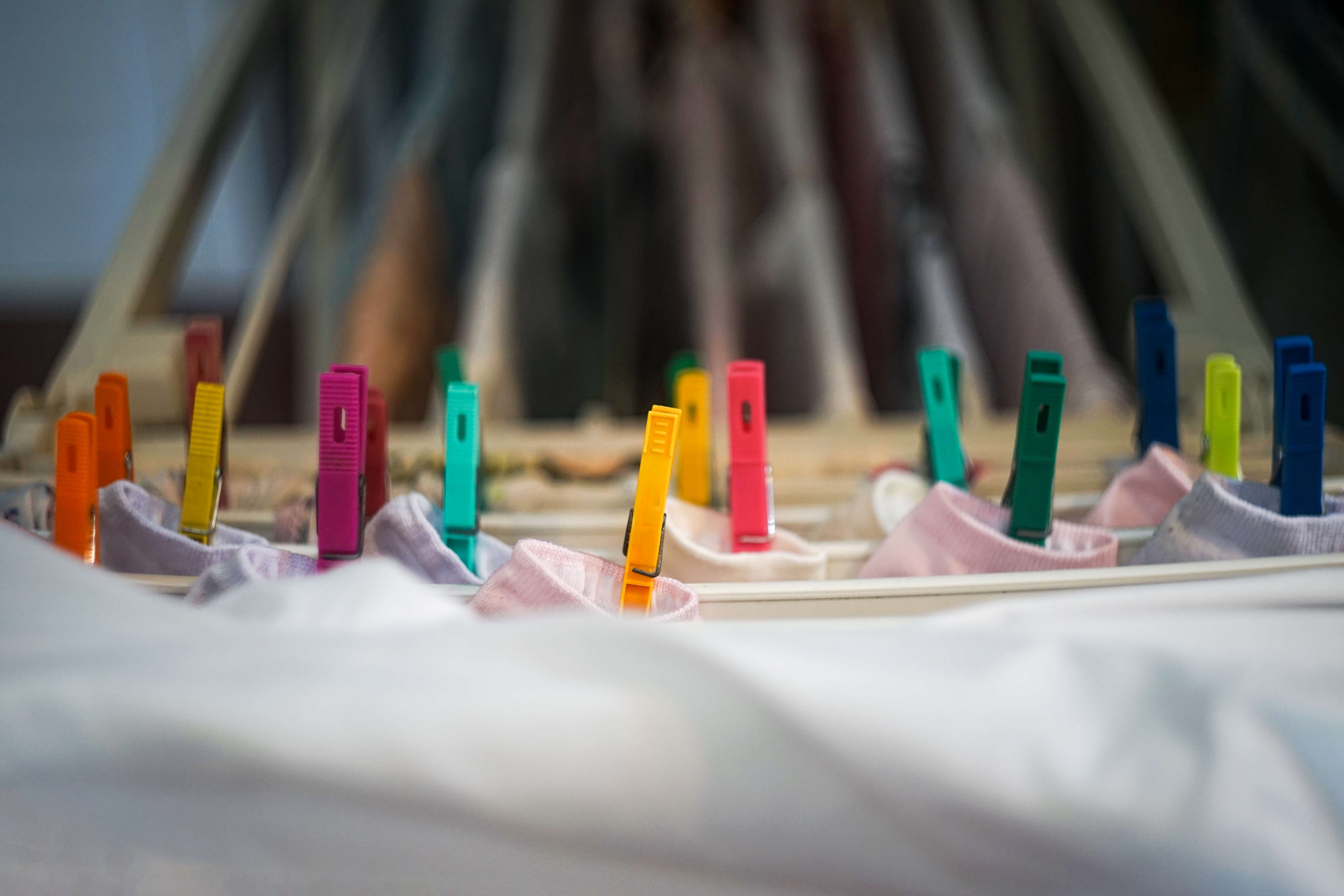 Clothes bein dried indoors, hanged by colorful clothespins.