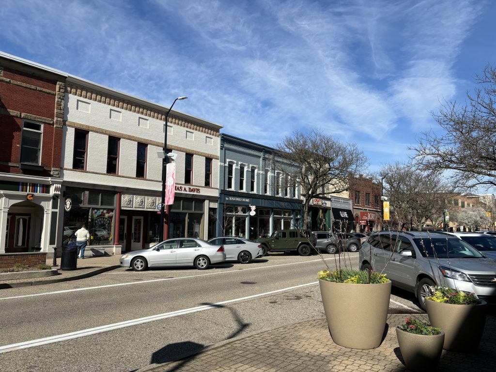 Small town America street. 8th Street in Holland Michigan. Storefronts, cars parked along the street, people walking.