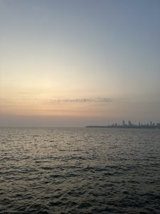 View larger photo: A calm river during sunset with a clear sky and a city skyline in the distance.