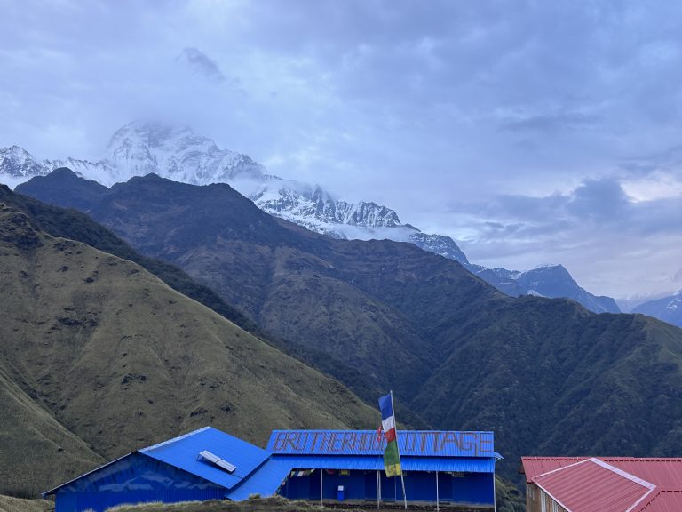 A close view of snowy mountains covered with clouds and greenery hills of Nepal.