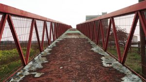 Red old rusty bridge passing over a road