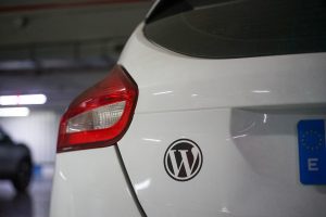Back view of a white car with a black WordPress sticker
