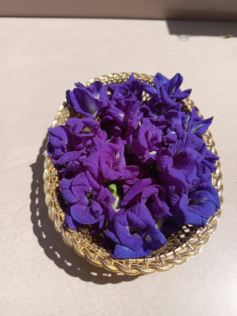 A decorative basket filled with vibrant purple flowers placed on a light surface.