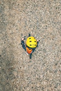  Kid on bike with yellow helmet on gravel, bird-eye view
