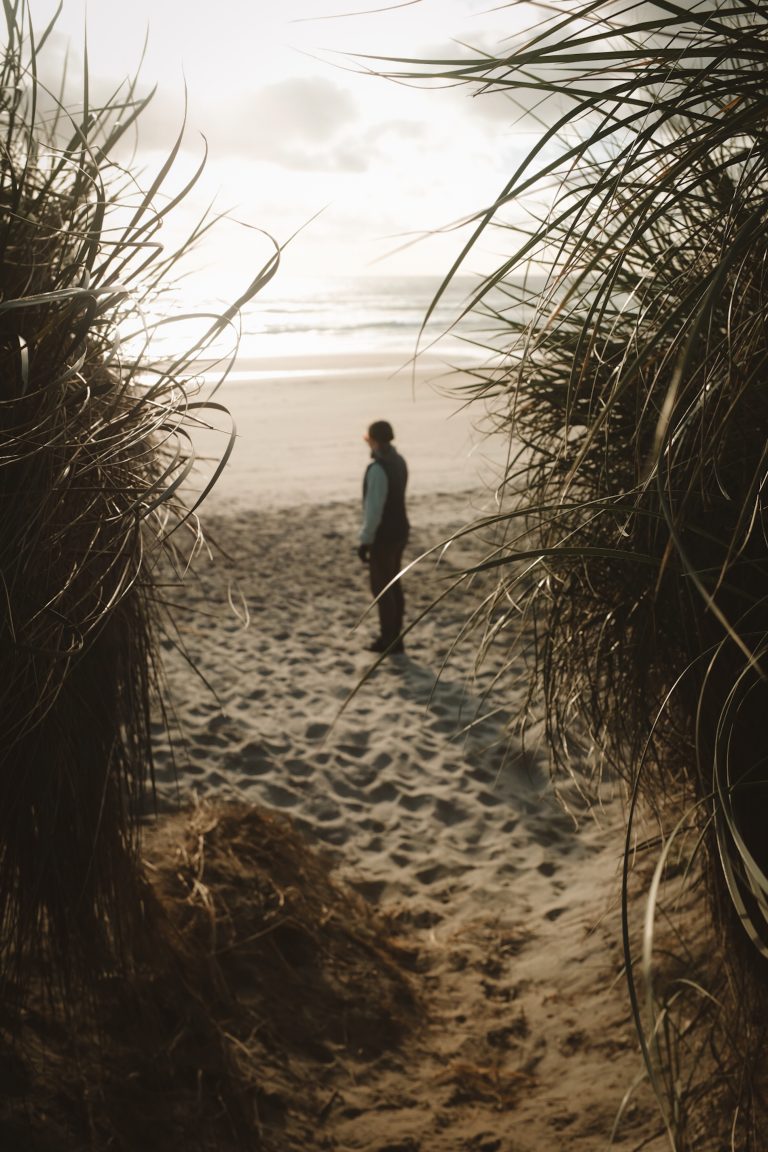 View between a sandbank of a person looking out onto a beach.