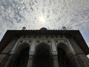 View of Isa Khan's Mosque from the ground looking up at a sunny and cloud sky (New Delhi, India)
