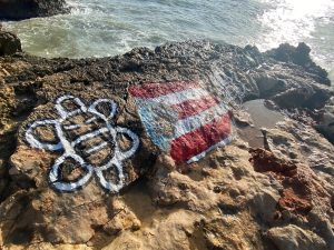 Rocky beach coast with Tiano Native symbol and Puerto Rico Flag 