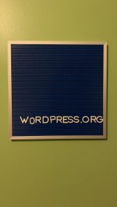 Green wall with a blue letter board with white letters spelling out "www.ads-software.com"