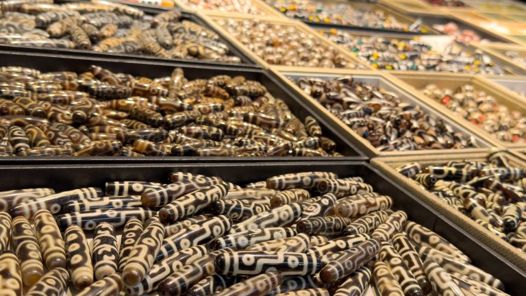 Sloping downwards from the left-hand side, the image shows trays of polished beads, there are thousands of them.  The beads closest to the viewer are in focus with the more distant ones falling out of focus.  The beads are grey, black and pale.