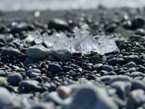 Small ice remaining from melted iceberg broken off a glacier resting on a black pebble beach (Diamond Beach, J?kulsárlón, Iceland)