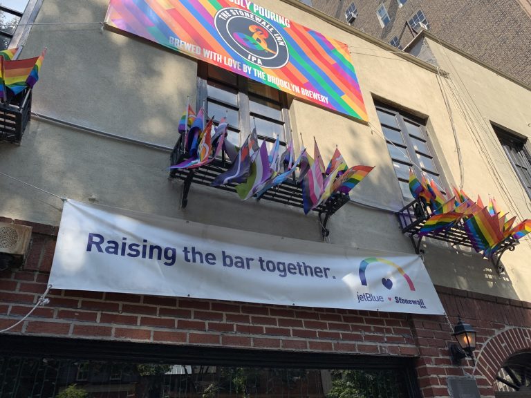 A photograph of the exterior of Stonewall Inn in New York with pride flags displayed outside.