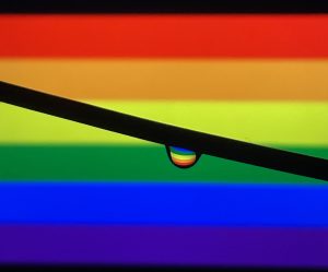  A water droplet with Pride Flag refelction and with the Pride Flag in background.
