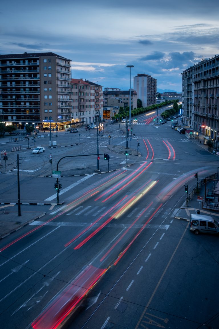 A long exposure photo of a busy intersection in the evening, with light trails from passing vehicles, taken from an elevated position.