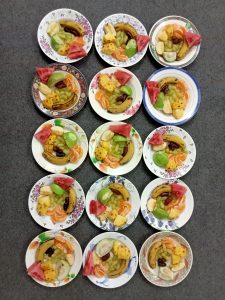 Different fruits including banana, pineapple, watermelon, apple, etc are on the plates and ready to serve. The plates are different colors, and the size is same. 