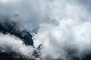 Cloud-covered mountains with dark, rugged cliffs partially visible through dense fog.