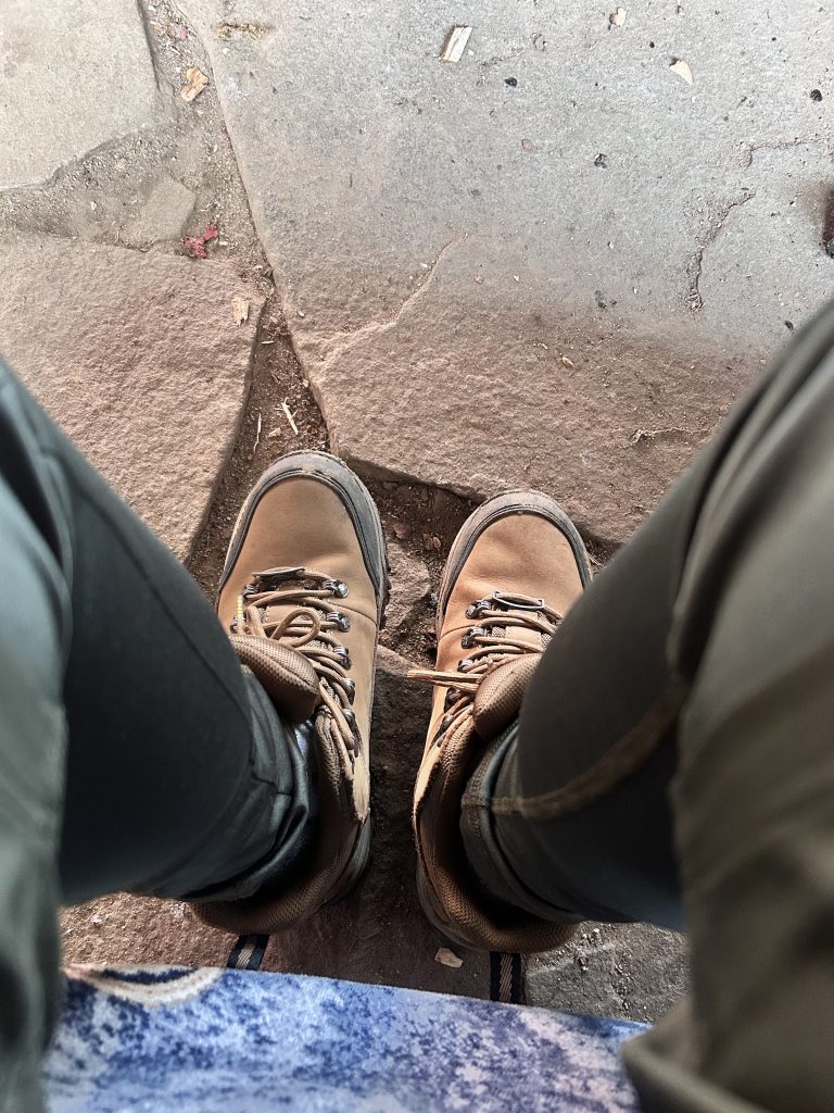 Looking down a pair of legs at hiking boots.