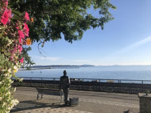 The Promenade at West Beach, White Rock, featuring a scenic walkway with a bench and a statue, overlooking the calm waters.