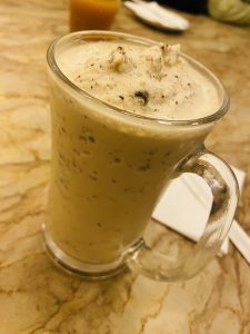 A glass mug filled with creamy Cafe Freddo is placed on a marble surface.