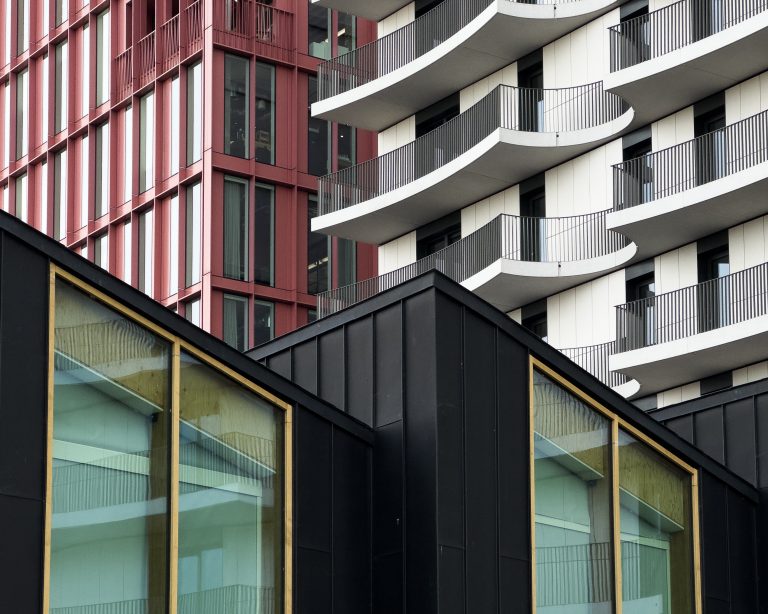 An abstract view of a group of buildings.  The buildings are close together and feature differing modern styles and colours.